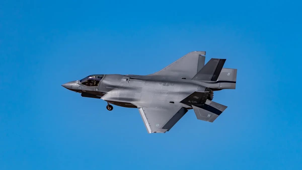 Dynamic shot of a F-35 fighter jet in flight against a clear blue sky.