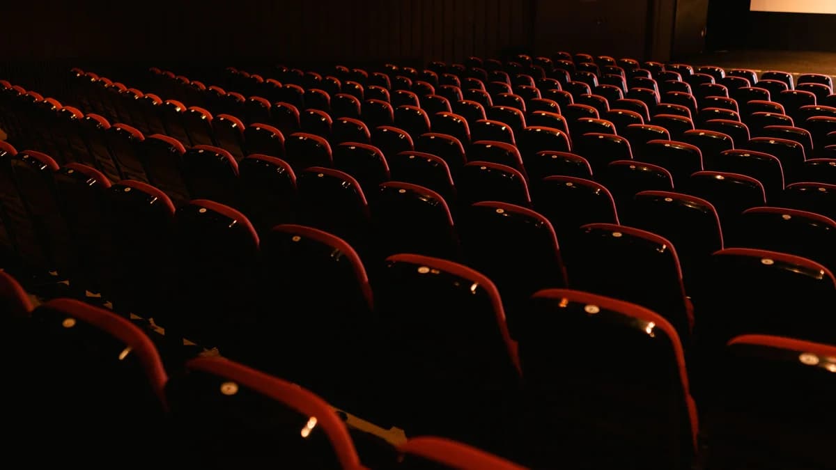 Rows of empty red seats in a darkened movie theater, awaiting audience.